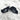 Two black masks with shark design and 'Mauna Experimental' branding on sandy surface